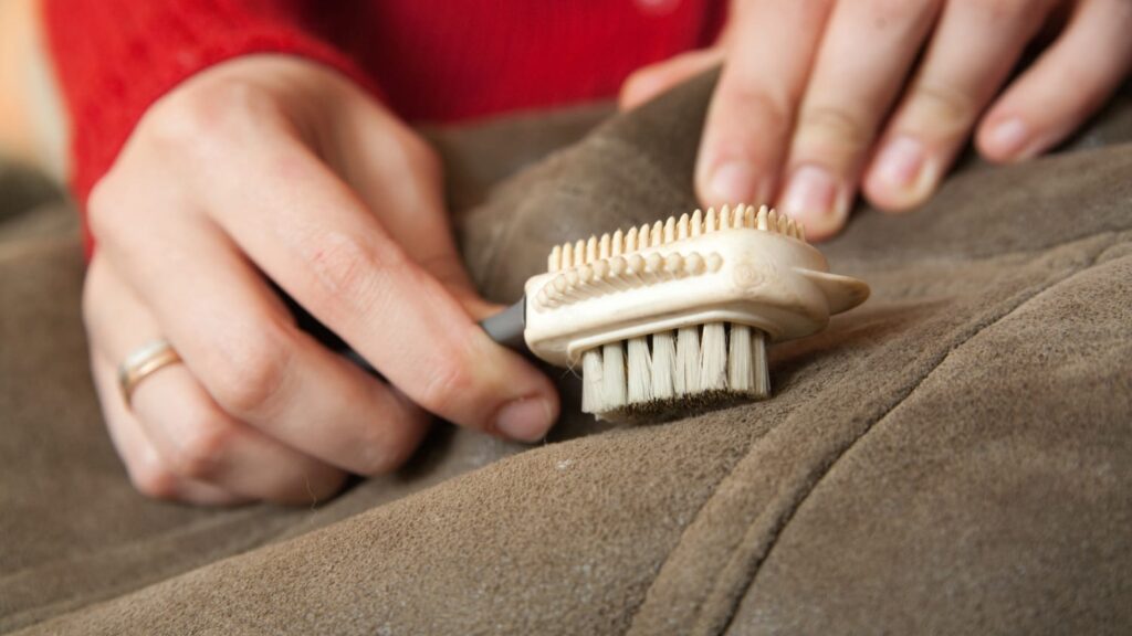 Vlekken uit bankbekleding verwijderen met een zachte borstel op suède stof