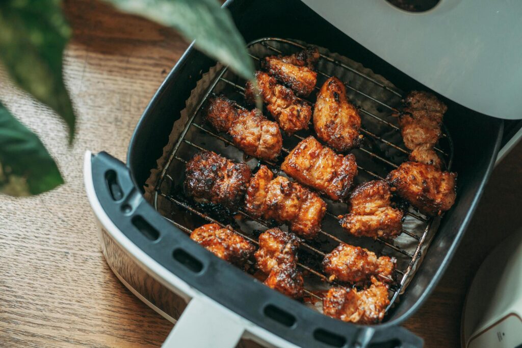 Kipstukjes liggen in airfryer mandje op rooster klaar om te bakken