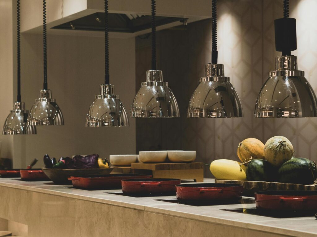 Buffet met warme gerechten onder hanglampen en fruit op toonbank in restaurant