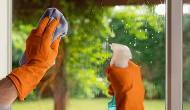 Persoon poets ramen met handschoenen aan door middel van een doek en sop