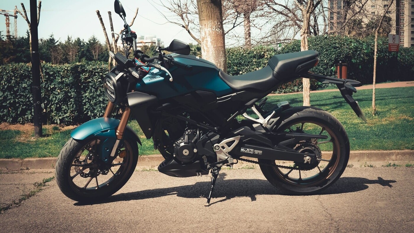 Moderne motorfiets geparkeerd langs de weg in een groene omgeving met bomen en struiken.