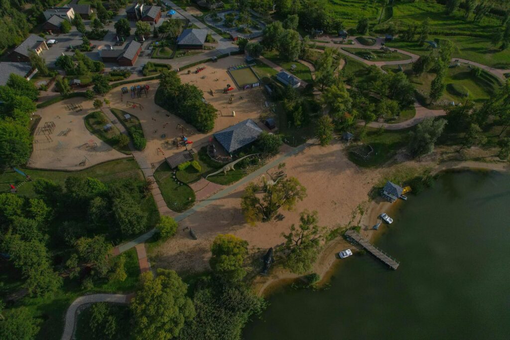 Luchtfoto van recreatiegebied met strand, speeltuin, paden en water met steiger