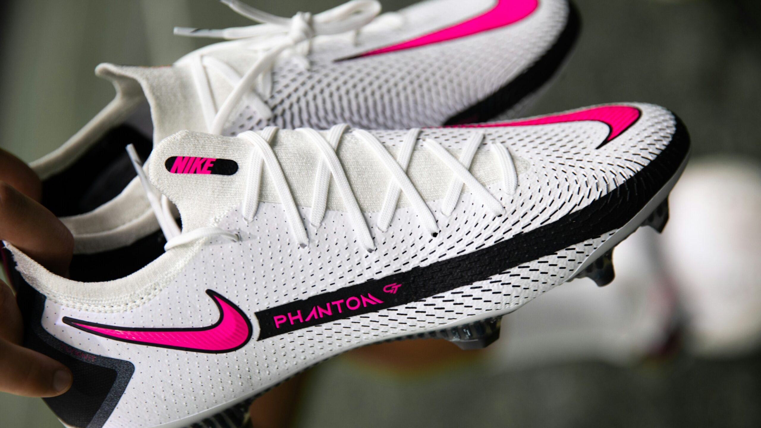 Witte Nike Phantom GT voetbalschoenen met roze accenten en schone noppen, klaar voor gebruik