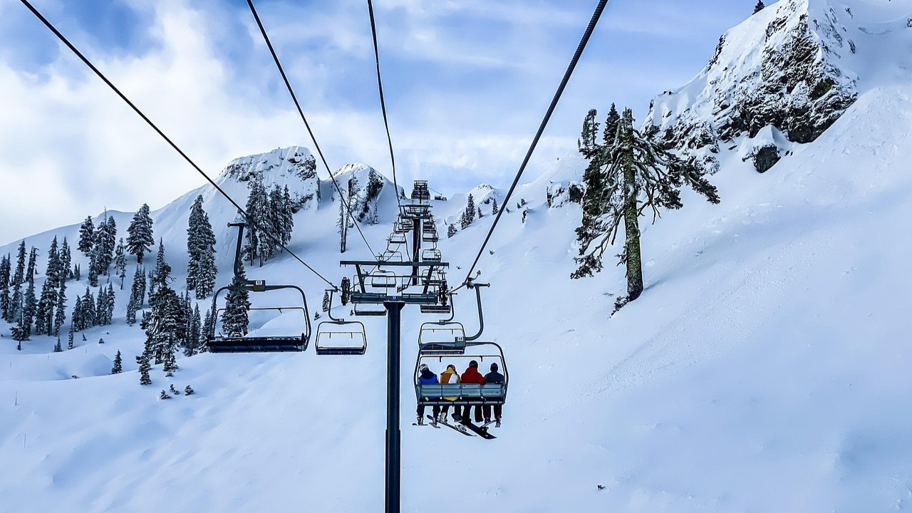 Stoeltjeslift met ski&euml;rs in kleurrijke wintersportkleding op een besneeuwde berg, ideaal voor wintersportkleding onderhouden.