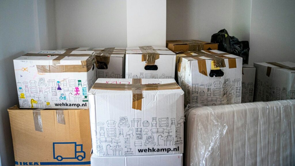 Dozen met tape en labels staan klaar in lege kamer tijdens woning leegmaken