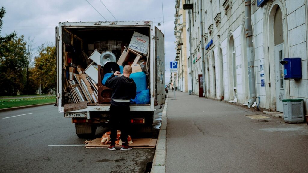 Man laadt volle vrachtwagen in tijdens woning leegmaken aan een stadsstraat